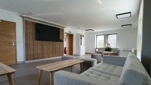 A modern living room with a grey sofa, wooden coffee table, and a flat-screen TV mounted on the wall. - Luxury Family Holiday Home With Wellness (Weiswampach)