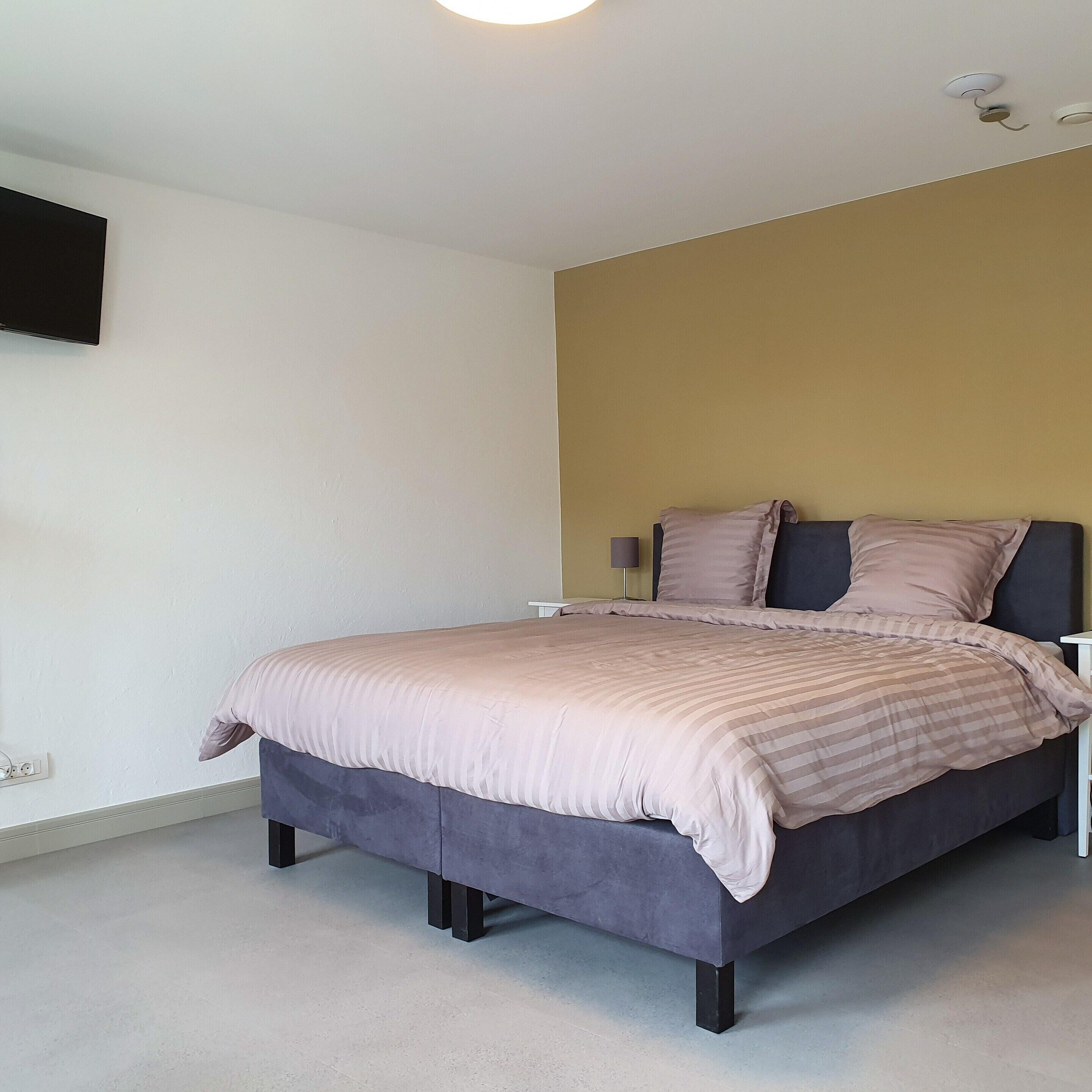 Ein Schlafzimmer mit einem Bett, Nachttischen und einem am Wand montierten Fernseher.