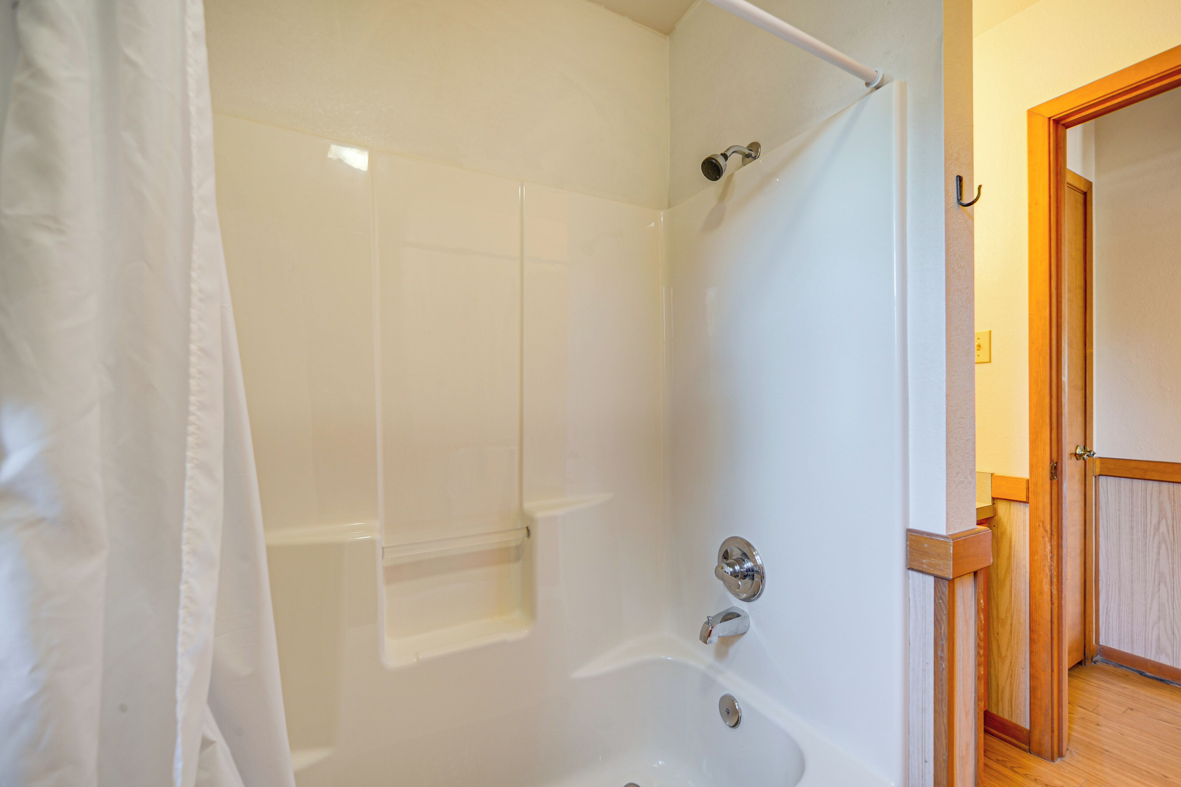 Une salle de bain avec une baignoire, une douche et une porte en bois.