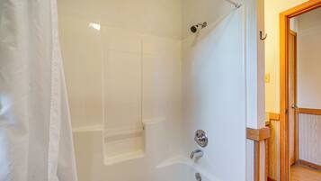 Une salle de bain avec une baignoire, une douche et une porte en bois.