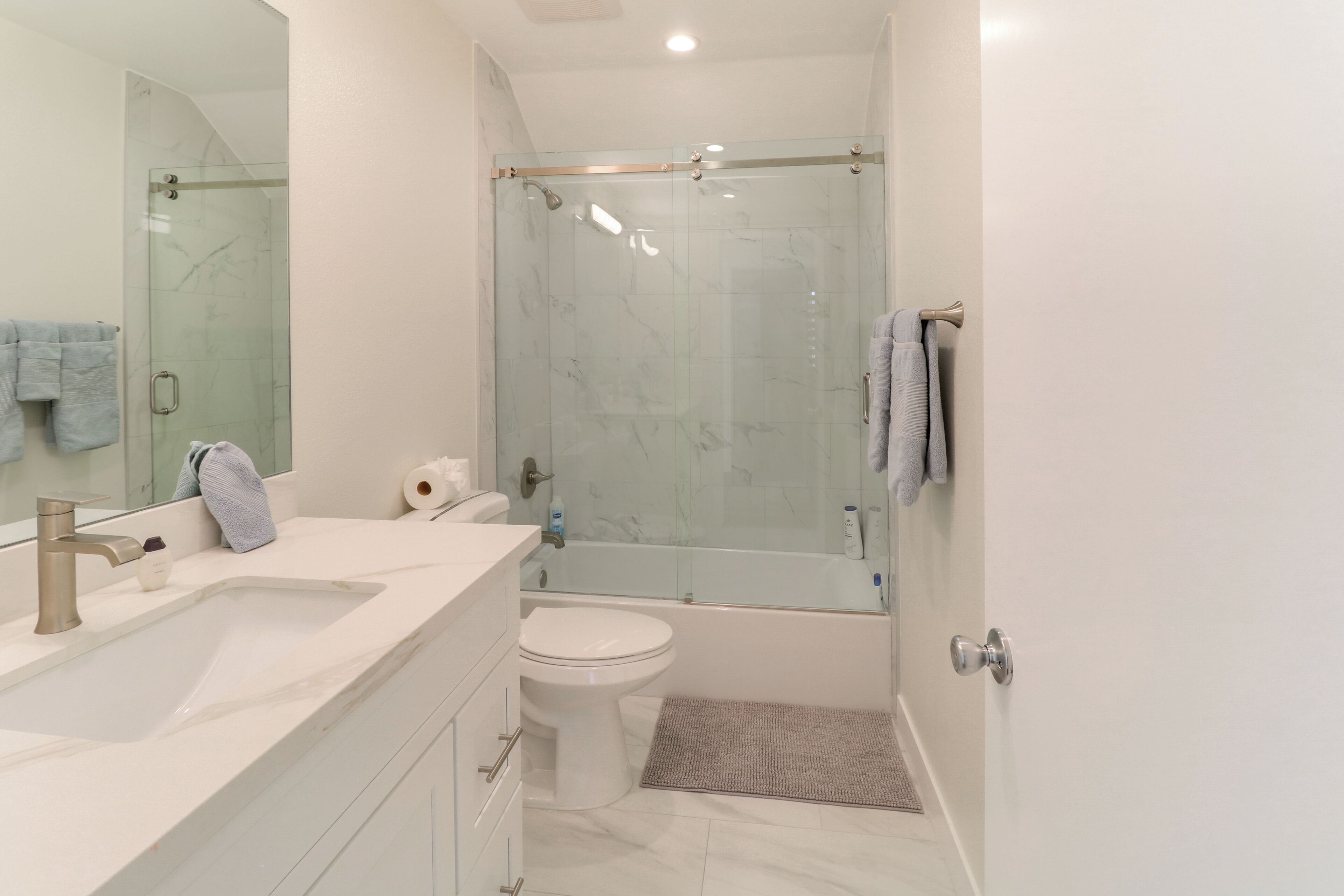 A modern bathroom with a glass-enclosed shower, a white sink, and a toilet.