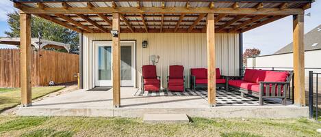 Une terrasse couverte avec un sol à carreaux, des chaises rouges et une pergola en bois.