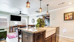 A modern kitchen with a large island, wooden cabinets, and pendant lighting. - Fenced Yard: Modern Barndominium in Amarillo! (Amarillo)