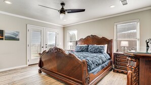 A bedroom with a large wooden bed, a ceiling fan, and a dresser. - Fenced Yard: Modern Barndominium in Amarillo! (Amarillo)