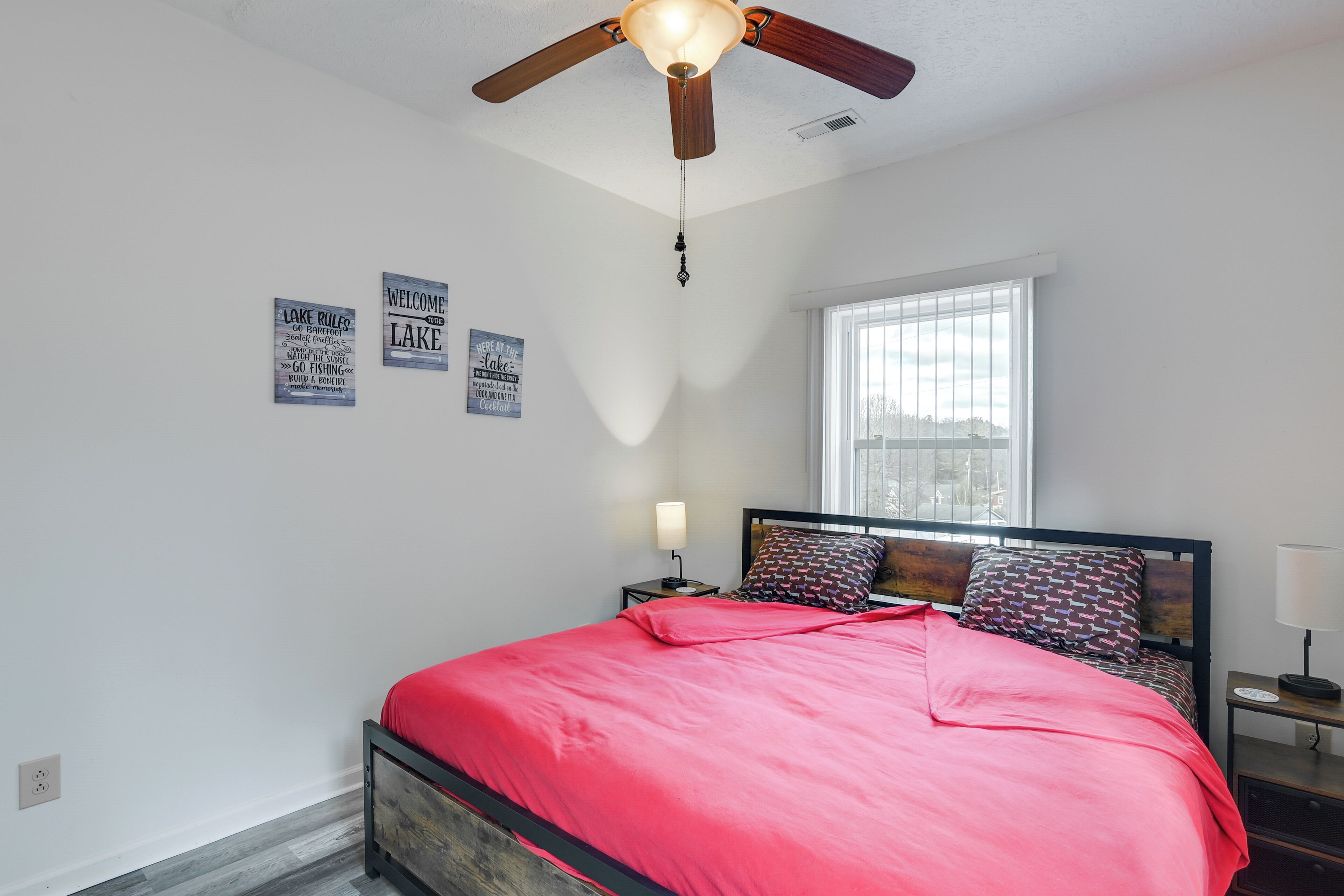 Een slaapkamer met een bed, plafondventilator, raam en wanddecoraties.