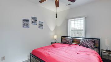 Een slaapkamer met een bed, plafondventilator, raam en wanddecoraties.