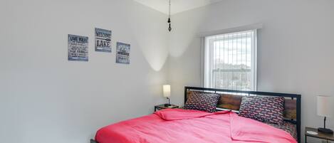 A bedroom with a bed, a ceiling fan, a window, and wall decorations.