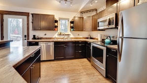 Una cocina moderna con armarios de madera oscura, electrodomésticos de acero inoxidable y encimera de madera.
