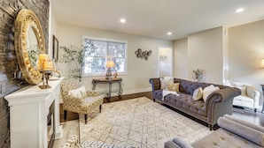A living room with a fireplace, patterned furniture, and a large mirror. - 6 Mi to Downtown - Spacious Home in Pittsburgh! (Pittsburgh)