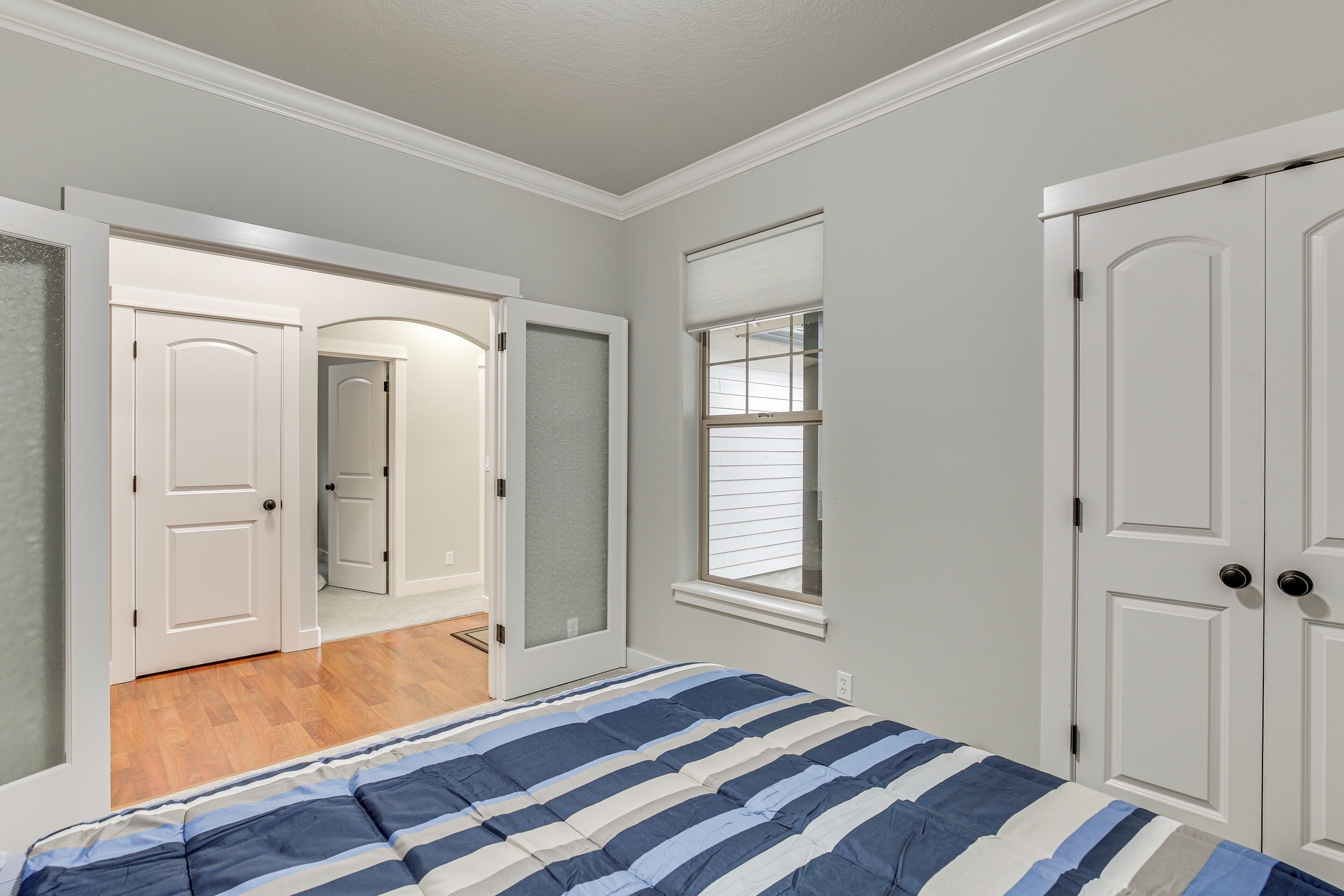 A bedroom with a bed, a closet, and a door leading to another room.
