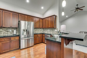 A modern kitchen with wooden cabinets, stainless steel appliances, and a black granite countertop.