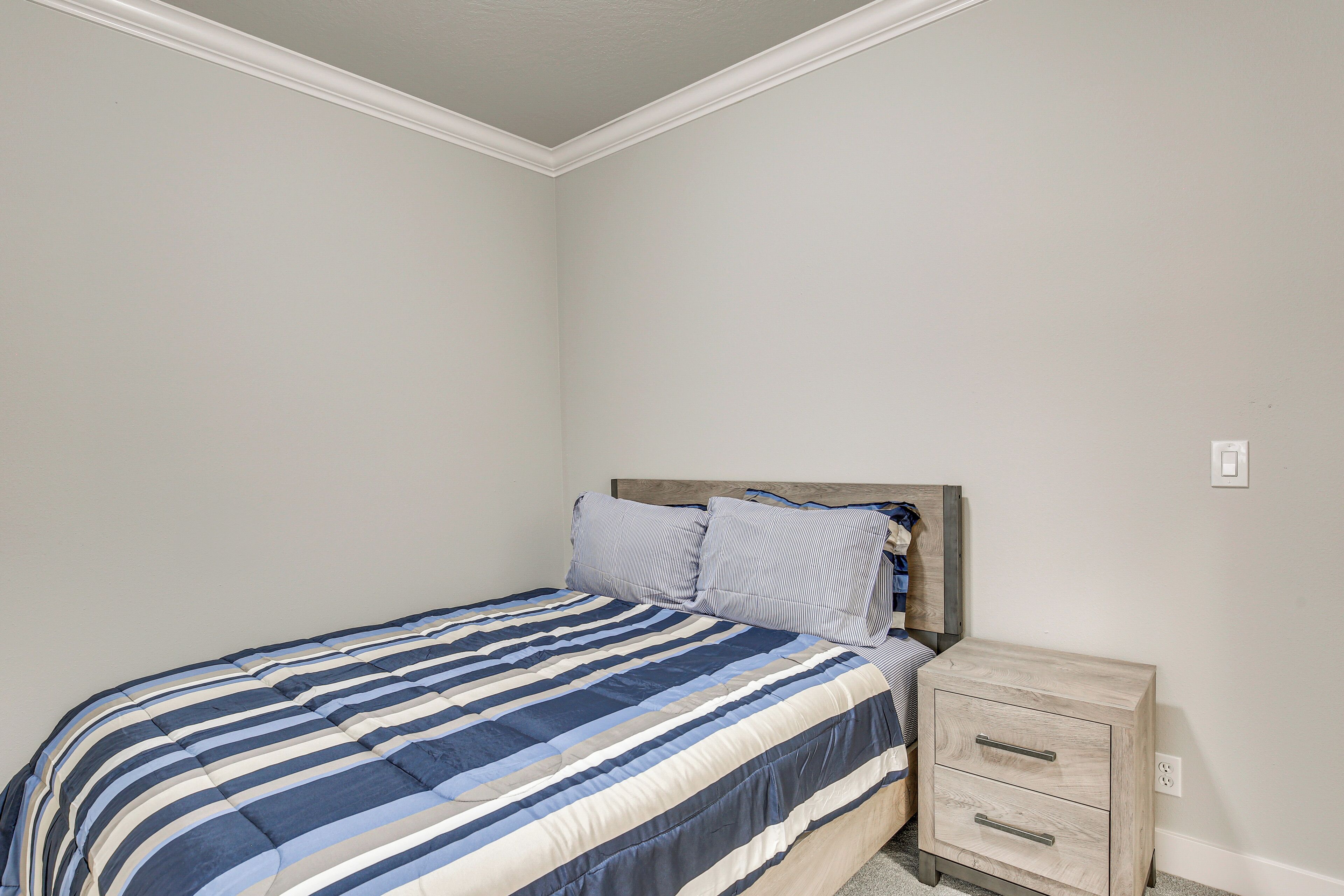 A bedroom with a bed, a nightstand, and a wall socket.