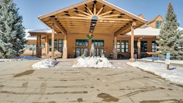A building with a covered entrance, snow accumulation, and a sign indicating handicapped parking.