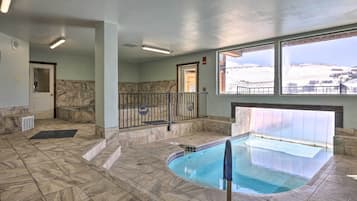 An indoor swimming pool with a view of a snowy landscape through large windows.