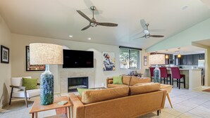 A modern living room with a sofa, a coffee table, a fireplace, and a TV mounted on the wall. - Condo w/ Patios & Community Pools in Palm Springs! (Palm Springs)