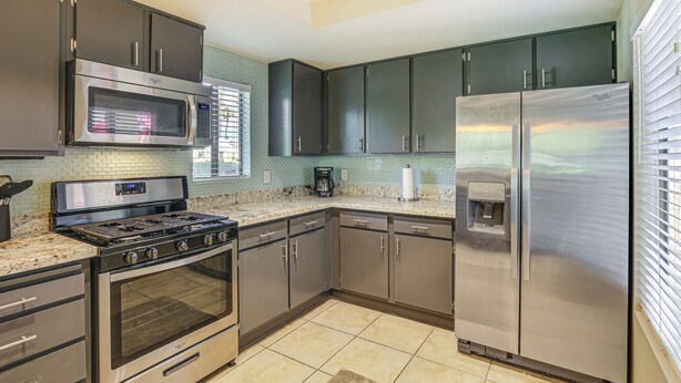 A modern kitchen with stainless steel appliances, dark cabinets, and a tiled backsplash. - Condo w/ Patios & Community Pools in Palm Springs! (Palm Springs)