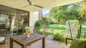A patio with a wooden table, a bowl of fruit, and a view of a well-maintained garden and mountains. - Condo w/ Patios & Community Pools in Palm Springs! (Palm Springs)