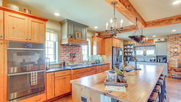 A spacious kitchen with wooden cabinets, stainless steel appliances, and a large island with stools. - 3 Mi to Dtwn: Charming Farmhouse in Mount Joy! (Mount Joy)