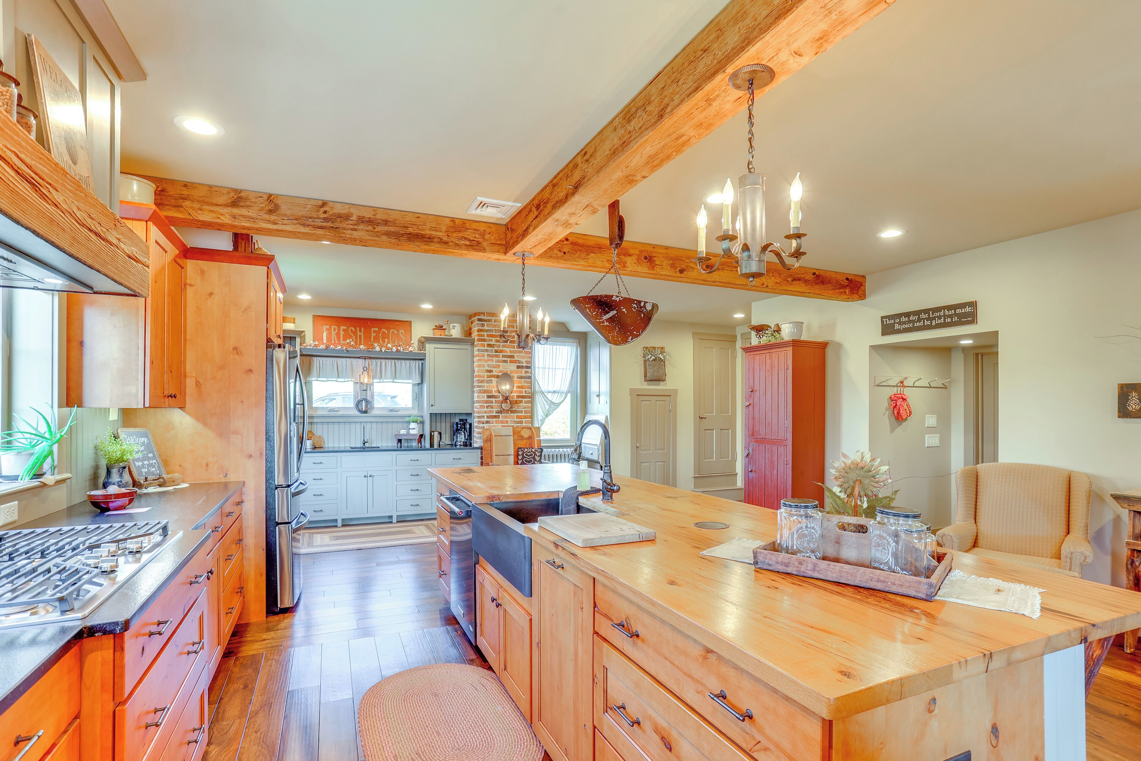 A spacious kitchen with wooden cabinetry, a large island, and a hanging light fixture.