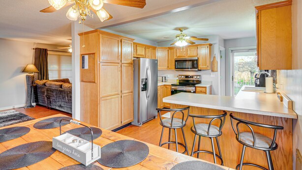 A modern kitchen with wooden cabinets, stainless steel appliances, a bar area, and a ceiling fan. - 2 Mi to Lake Cumberland Access: Home w/ Grill (Jamestown)