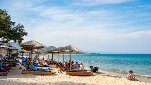 A beach with sun loungers and umbrellas, a clear sky, and the ocean. - Aristi House in Olimpiada (Aristotelis)