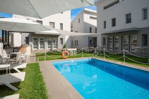A swimming pool with a white fence and lounge chairs, surrounded by modern buildings. - Aristi House in Olimpiada (Aristotelis)