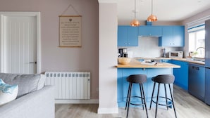 A modern kitchen with blue cabinets, a wooden island, and two black bar stools.