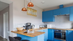 A modern kitchen with blue cabinets, a wooden countertop, and a built-in oven.