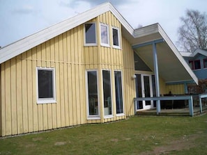 A yellow building with a gabled roof, large windows, and a covered porch area. - Skandinavisches Ferienhaus in Mirow (Mirow)