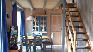 Ein Holzinnenraum mit Essbereich, einer Treppe und einem Fenster mit Vorhängen.