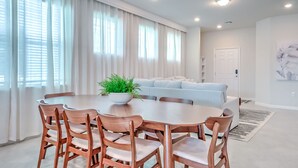 A modern dining area with a round table, wooden chairs, and a potted plant. - 16235 Luxury Retreat Your Perfect Getaway Family Home (Clermont)