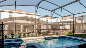 A swimming pool with a glass enclosure, surrounded by a patio area with seating and plants. - 16235 Luxury Retreat Your Perfect Getaway Family Home (Clermont)