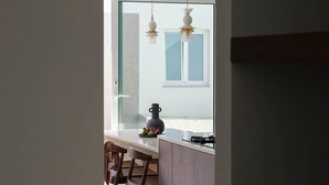 A modern kitchen with a large window, two pendant lights, and a dining area with wooden chairs. - Casa da F in Parchal (Lagoa)