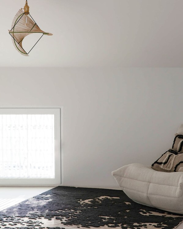 A bedroom with a bed, a window with blinds, a patterned rug, and a hanging light fixture. - Casa da F in Parchal (Lagoa)