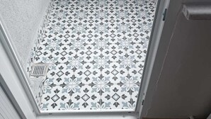 Un petit balcon fermé, doté de carreaux décoratifs, d’un plancher en bois et d’une porte donnant sur l’intérieur.