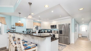 A modern kitchen with white cabinets, stainless steel appliances, and a central island.