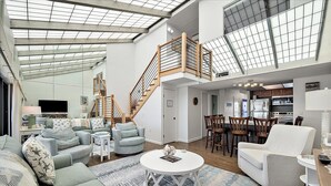 Un vaste espace de vie doté d’un haut plafond, d’un escalier et d’une cuisine.