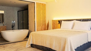 Una habitación de hotel moderna con una cama grande, una bañera y zona de ducha separada.