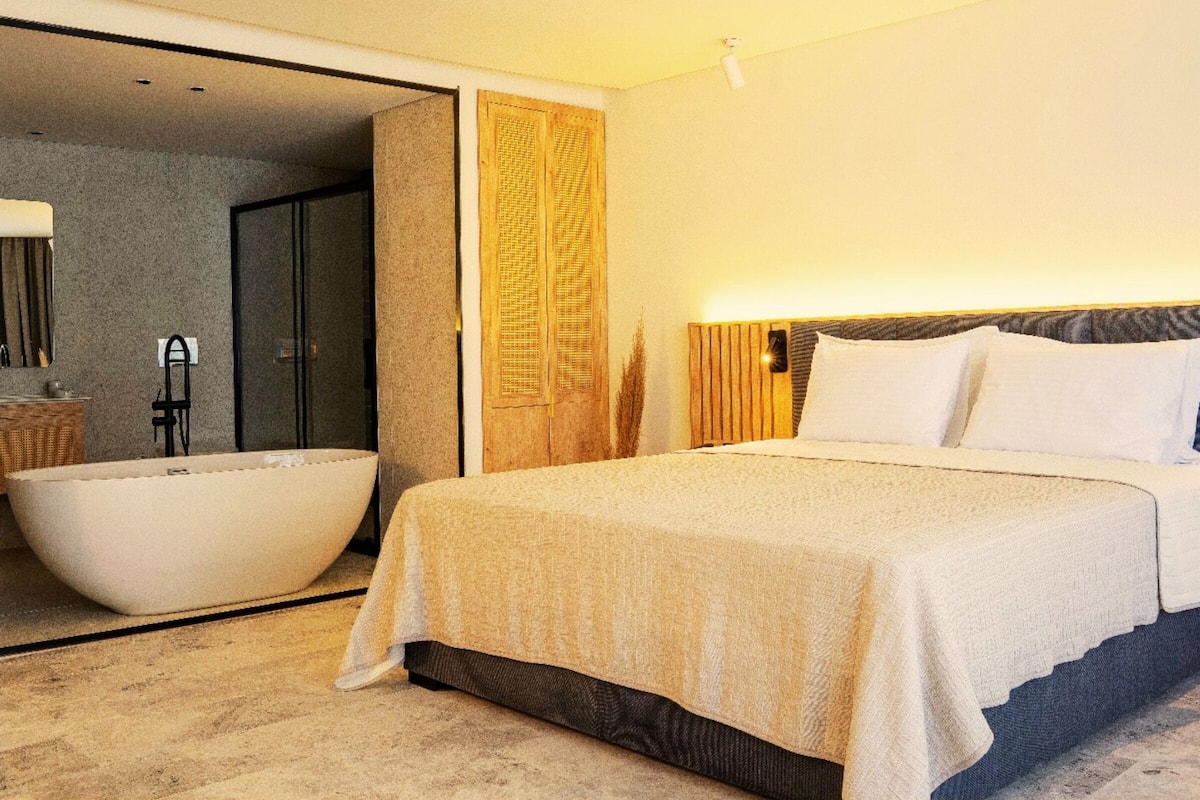 Una habitación de hotel moderna con una cama grande, una bañera y zona de ducha separada.
