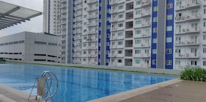 En modern hyresfastighet med en swimmingpool, balkonger och en klar himmel.