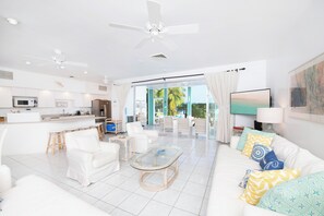 Ein modernes Wohnzimmer mit einem weißen Sofa, einem Glastisch und einem Deckenventilator.
