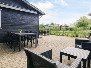 A patio area with outdoor seating and a wooden table. - 6 Person Holiday Home in Hadsund (Hadsund)