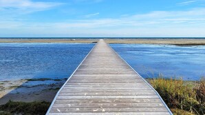 Un muelle de madera se extiende sobre aguas tranquilas bajo un cielo despejado.