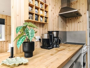 A kitchen with wooden cabinets, a coffee maker, a potted plant, and a white plate on the counter. - 6 Person Holiday Home in Hadsund (Hadsund)