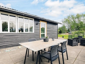 A patio with a table and chairs, a potted plant, and a lamp. - 7 Person Holiday Home in Hadsund (Hadsund)