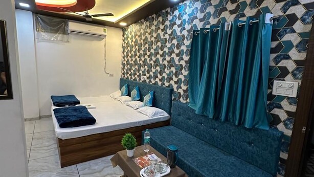 Een moderne kamer met een bed, een bank, een bijzettafeltje en een behang met patroon.