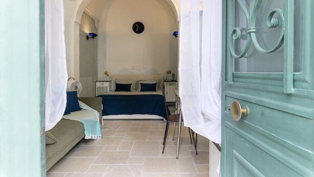 A bedroom with a bed, bedside tables, and a clock on the wall.