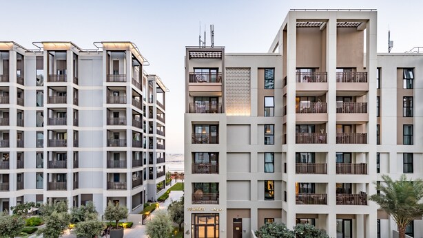 A modern multi-story residential building with balconies, a central courtyard with trees, and a visible entrance labeled "SUMMER".