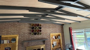 A room with exposed wooden beams, a brick wall, a fireplace, and a bookshelf.