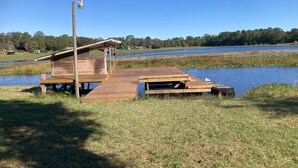 A wooden dock extending into a lake with a small shelter and a lamp post.